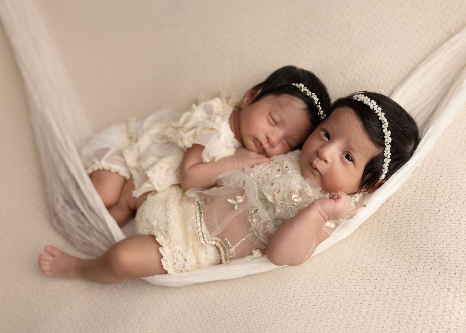 Twin newborn girls cuddle together sleeping in a hammock. Newborn photography Surrey Elizabeth Lang