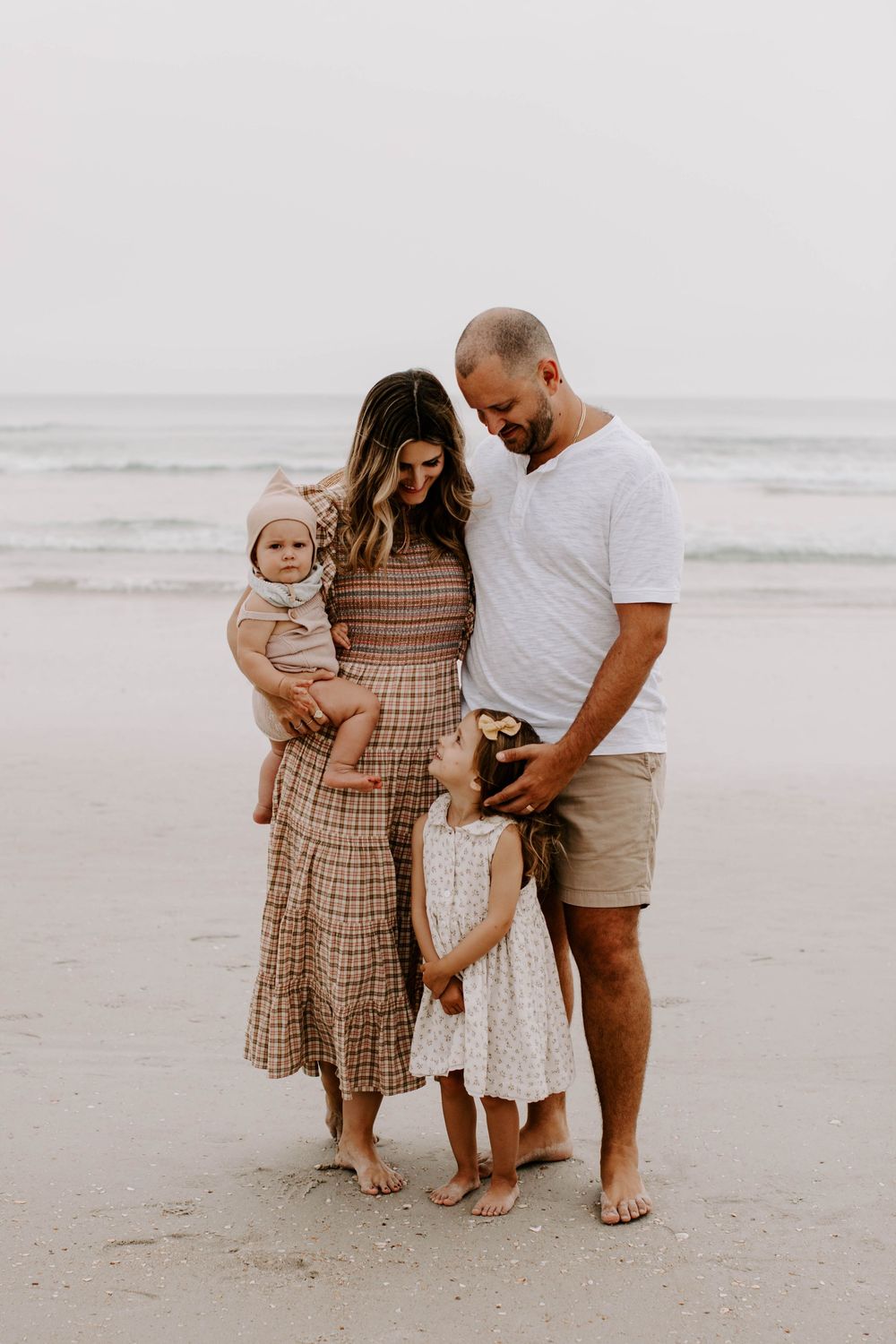 Candid family portrait on beach with matching casual outfits.