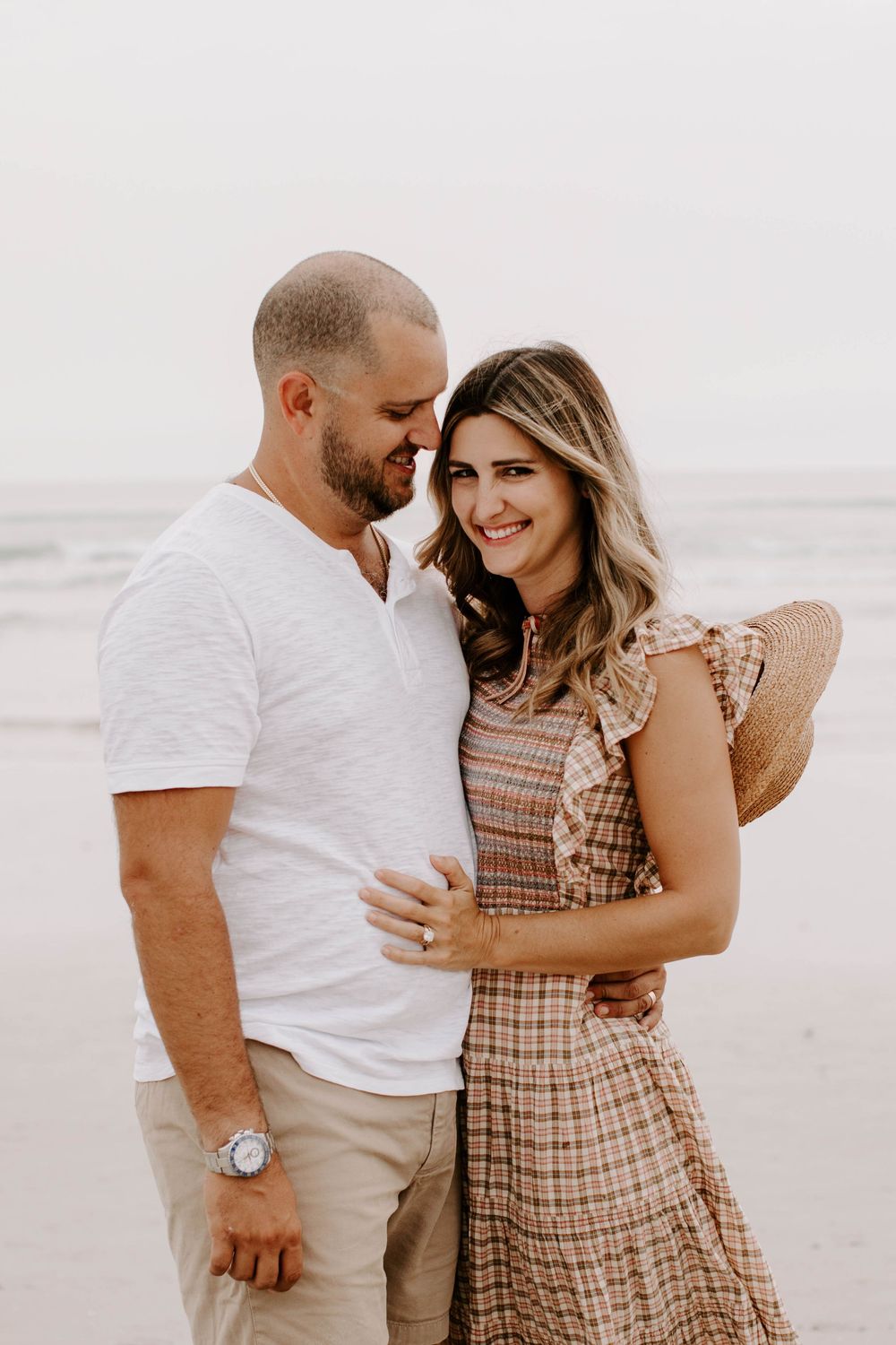 Romantic couple in casual attire sharing intimate moment on beach.