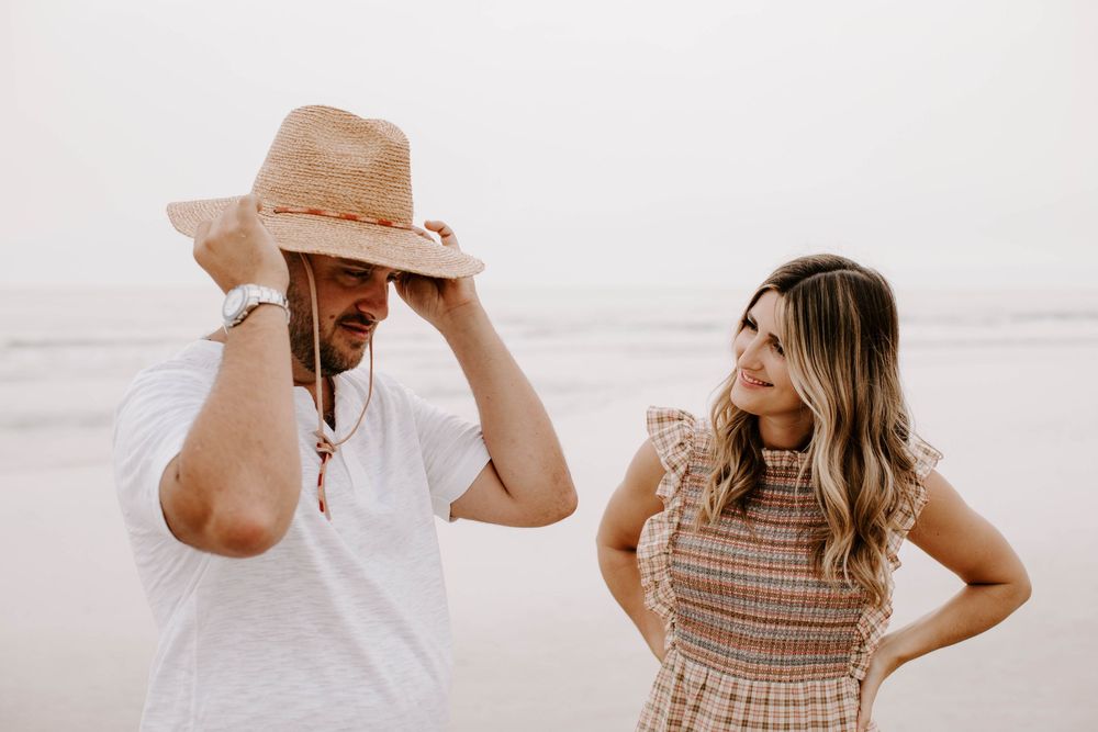 A couple shares an intimate moment together at the beach with soft lighting and neutral tones.