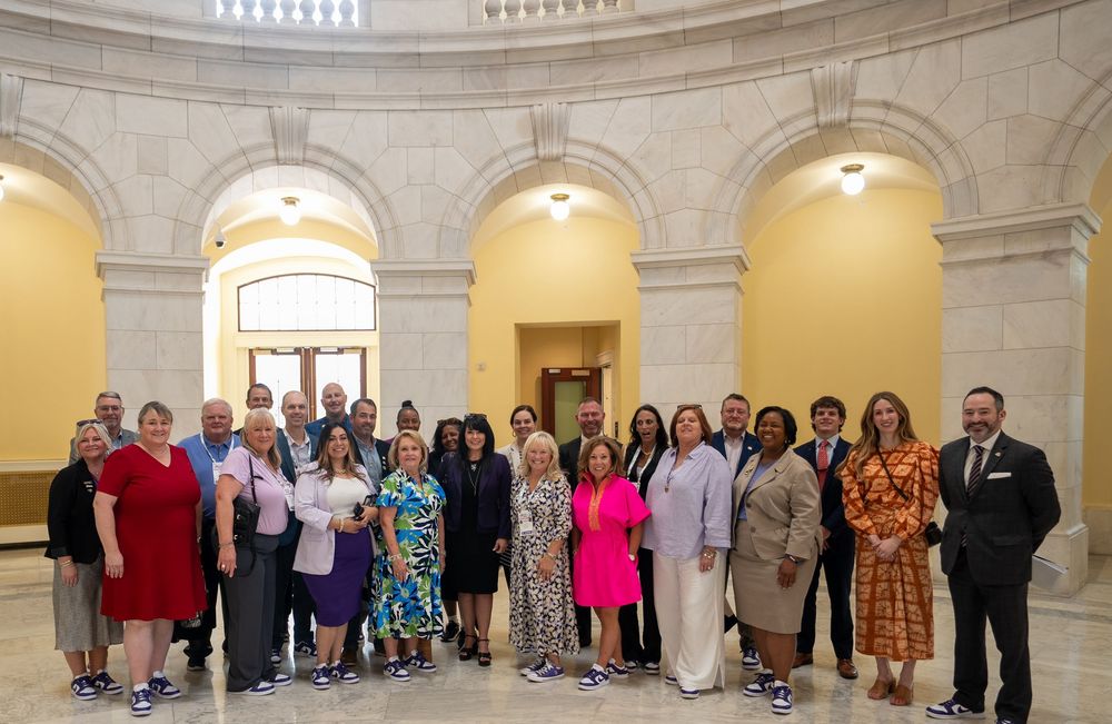 Group photo inside ornate government building with arched hallways and decorative architecture.