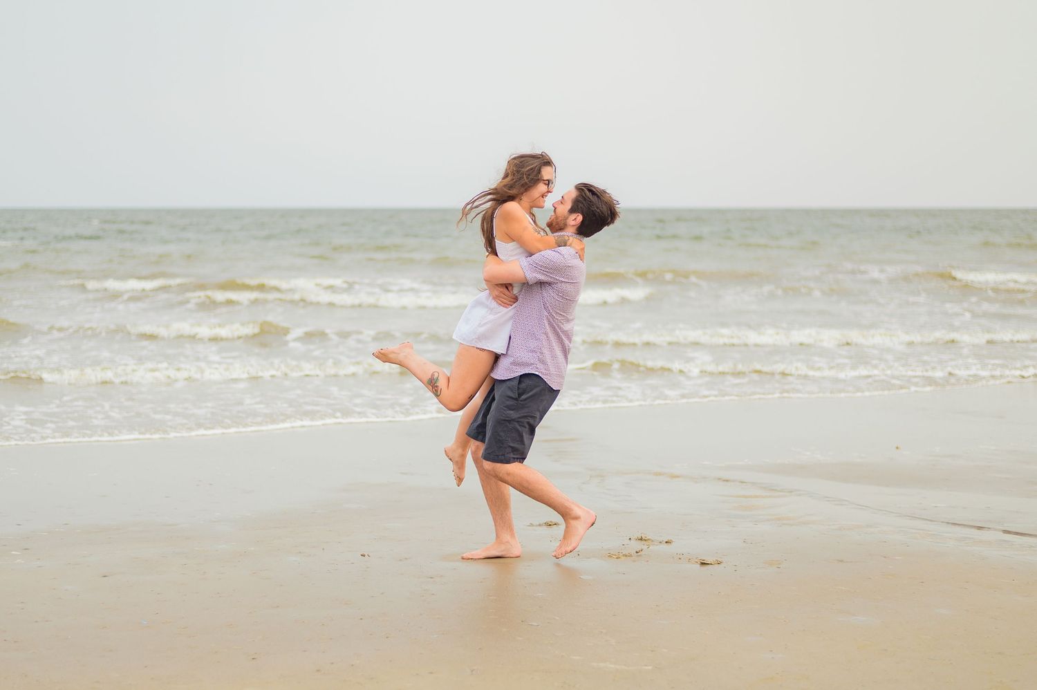 Joyful couple embracing on a misty beach shore.
