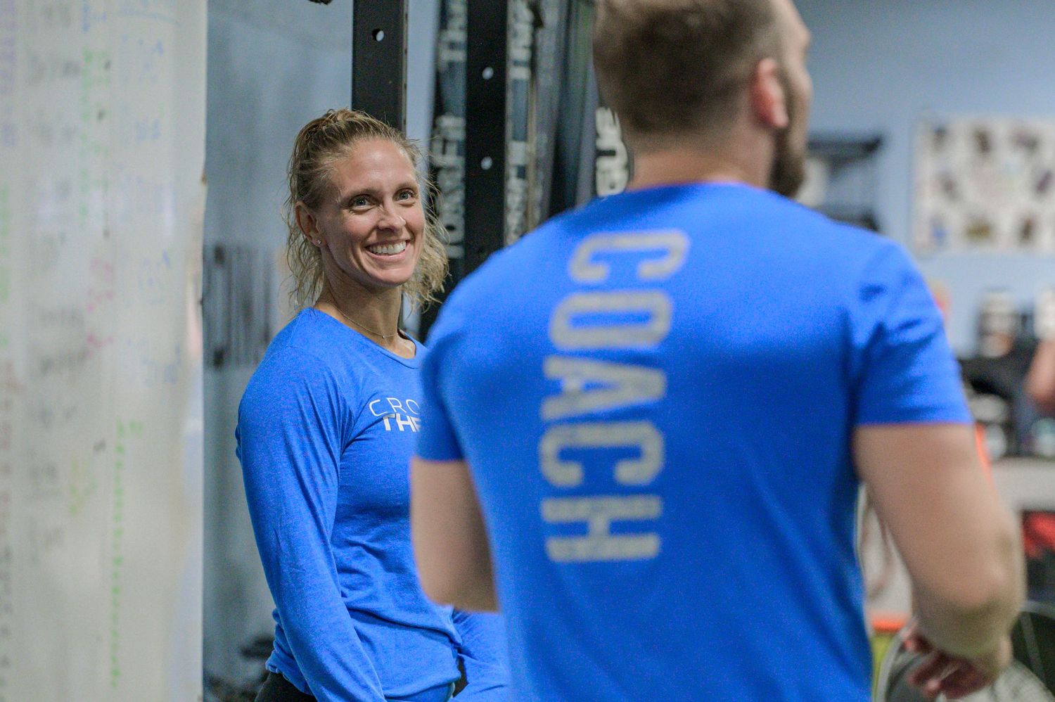 Two people in blue athletic wear interact during a fitness training session.