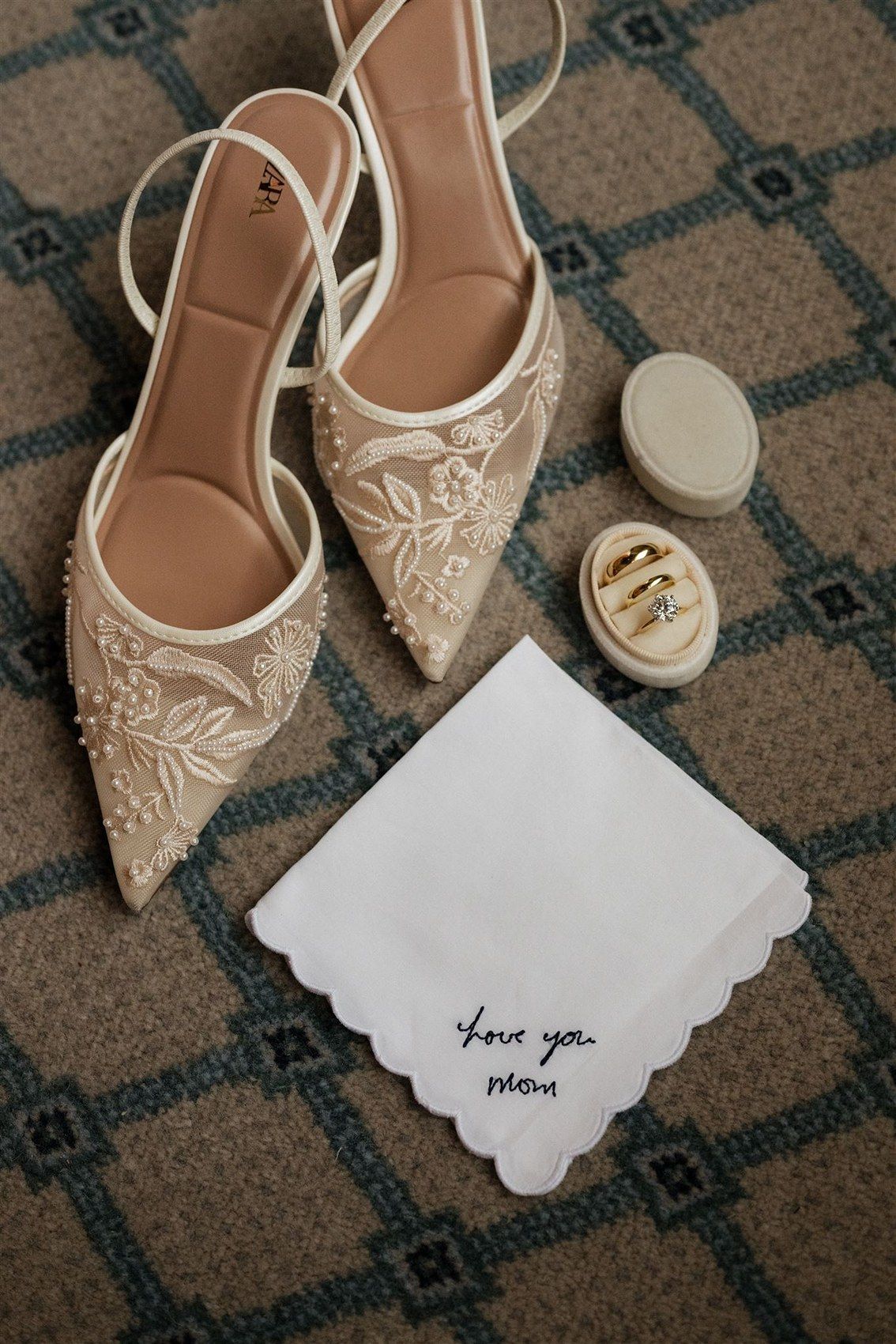 Elegant ivory lace bridal heels with slingback straps displayed next to a handwritten note and small wedding accessories.