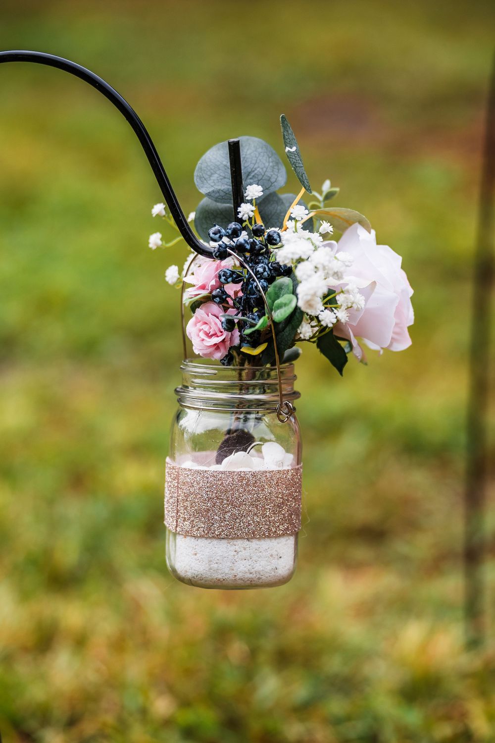 Mason jar hanging decorations with glitter and floral arrangements create an elegant rustic wedding display.