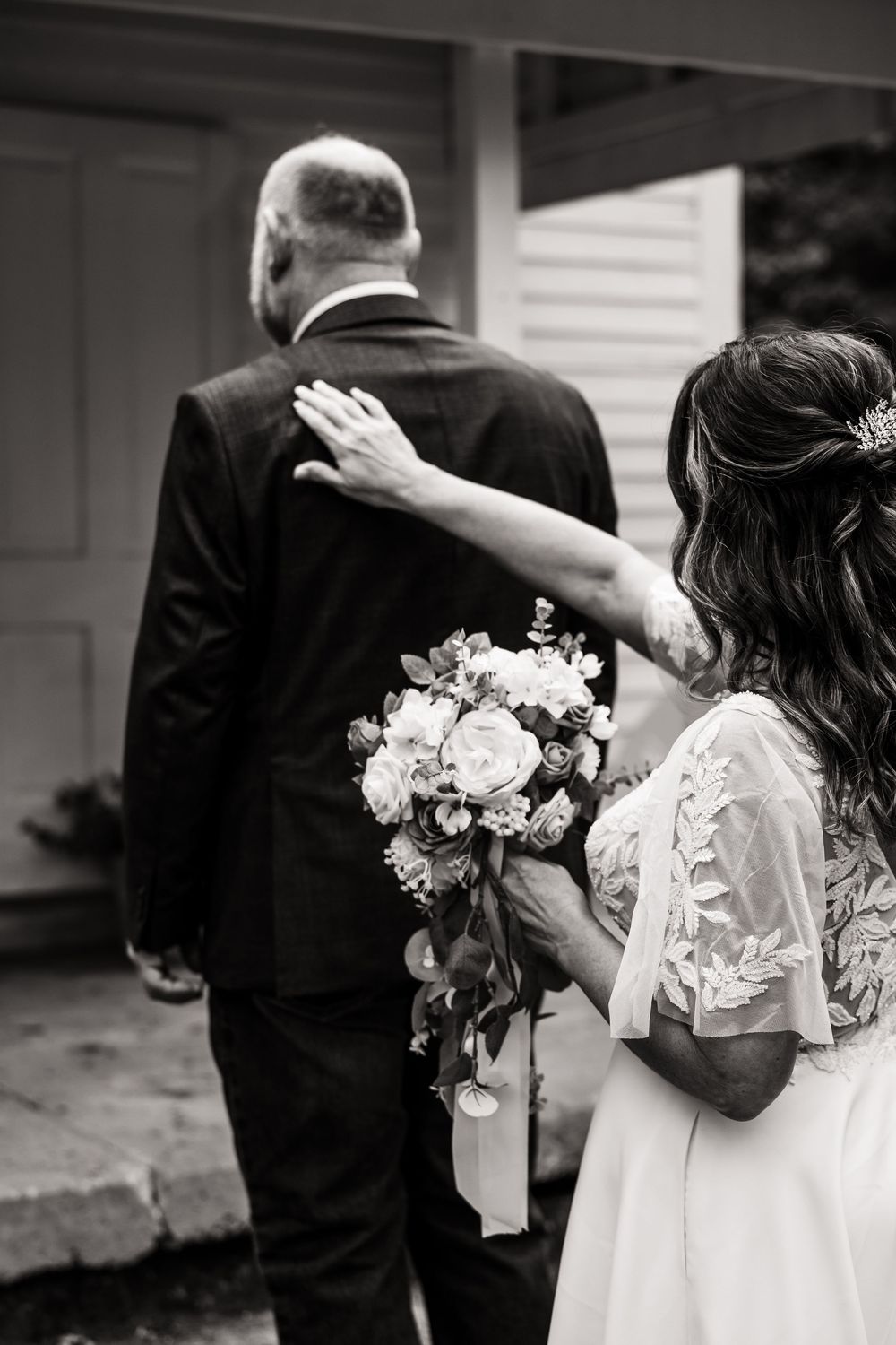 A bride holds a beautiful bouquet of roses and delicate flowers as she walks with her partner.