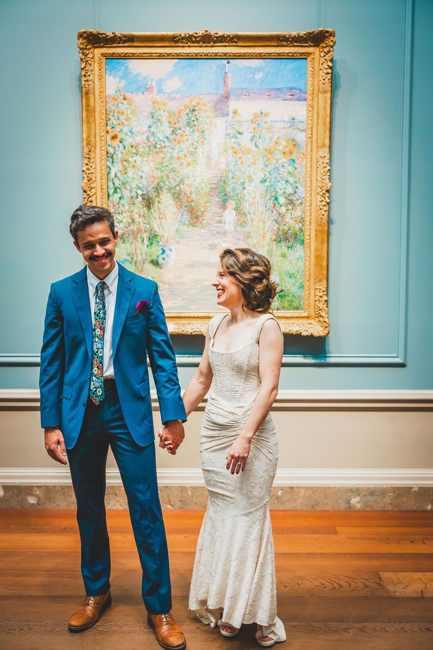 Art gallery sequence showing couple dancing playfully in front of framed Monet paintings on turquoise walls.