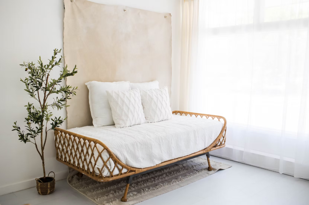 Minimalist rattan daybed with white cushions and pillows displayed at different angles in a bright sunlit room.