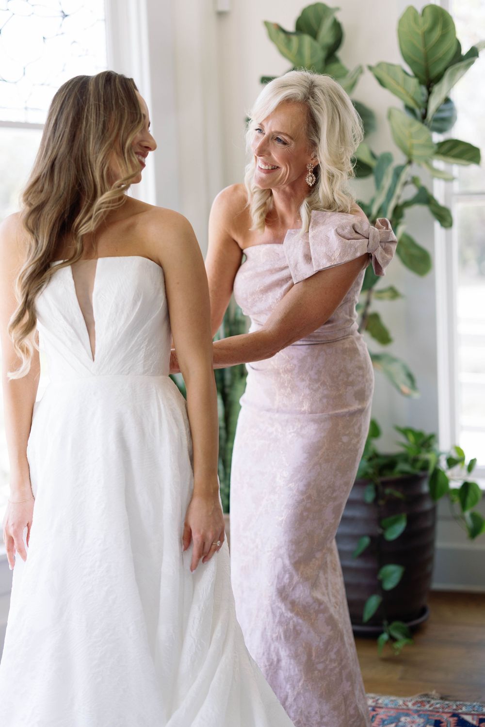A series of heartwarming moments between a bride in white and someone in pink sharing emotional embraces in a bright room.