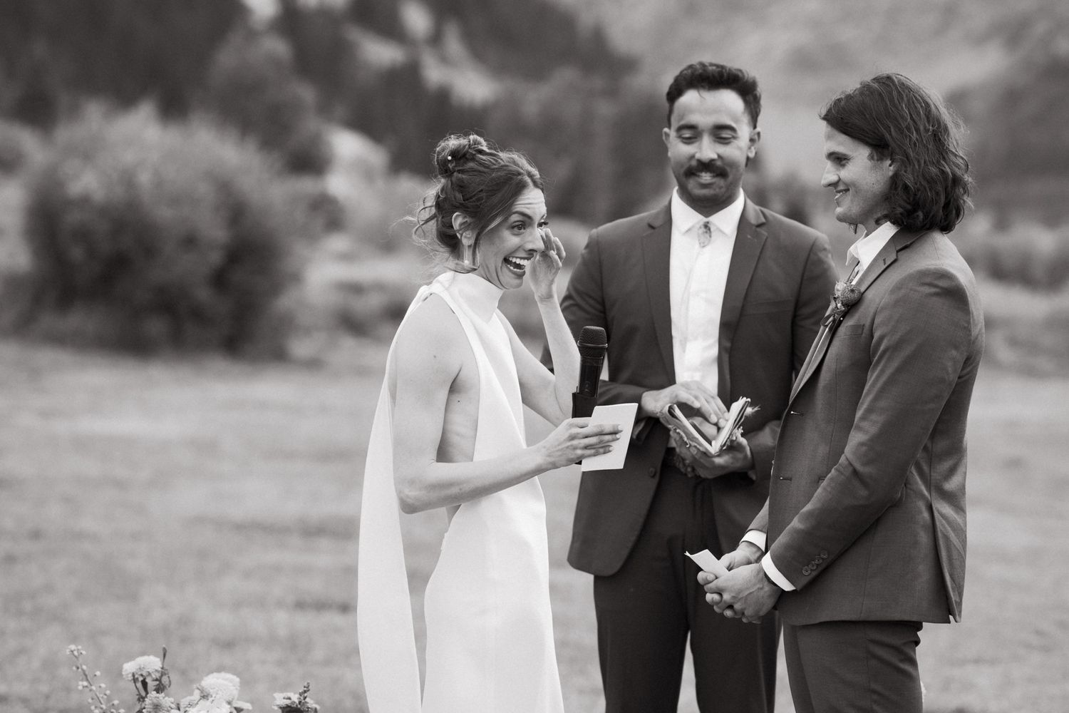 Wedding ceremony moment in black and white as couple shares emotional vows in outdoor setting.