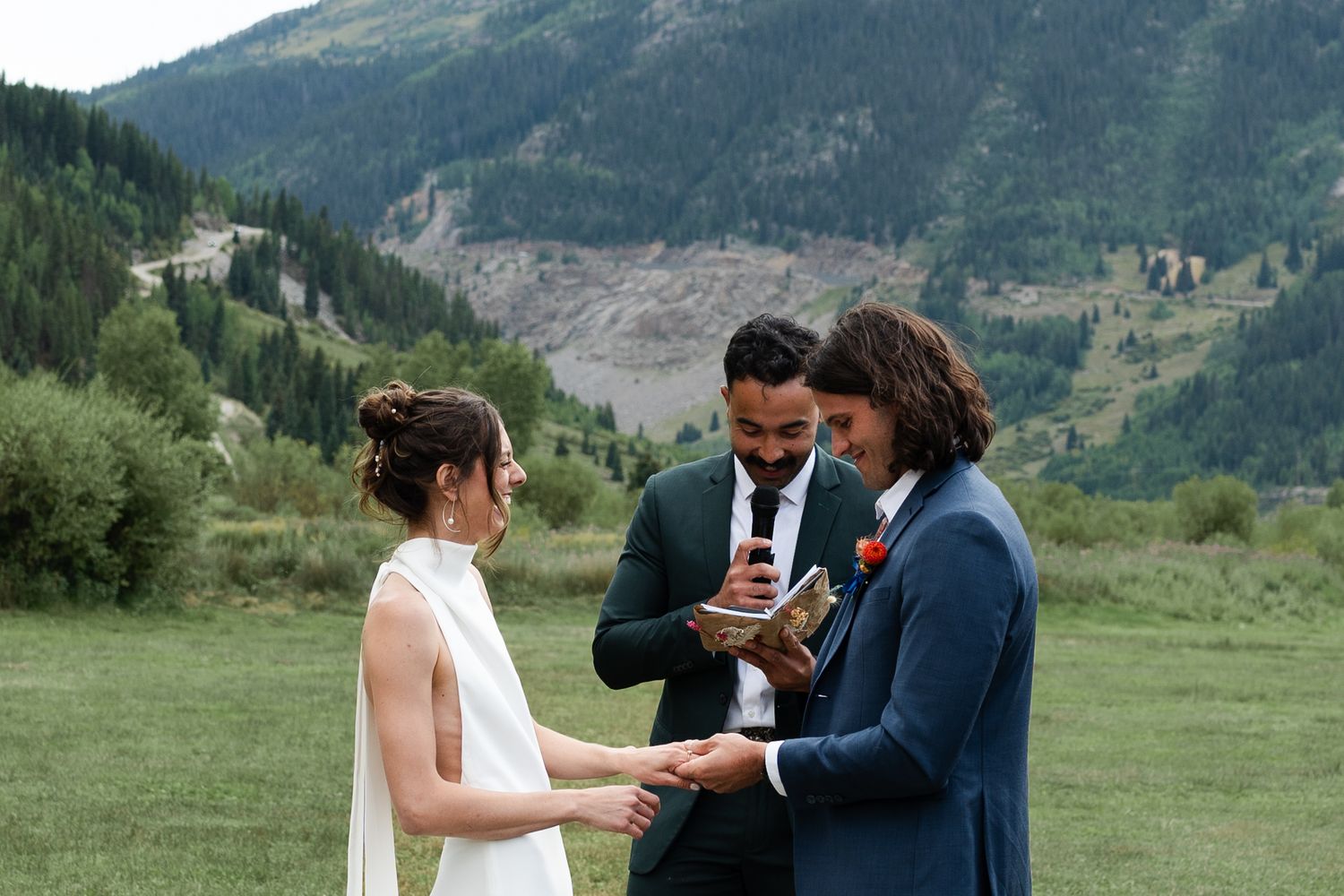 Intimate wedding ceremony with couple exchanging vows in front of mountain landscape.