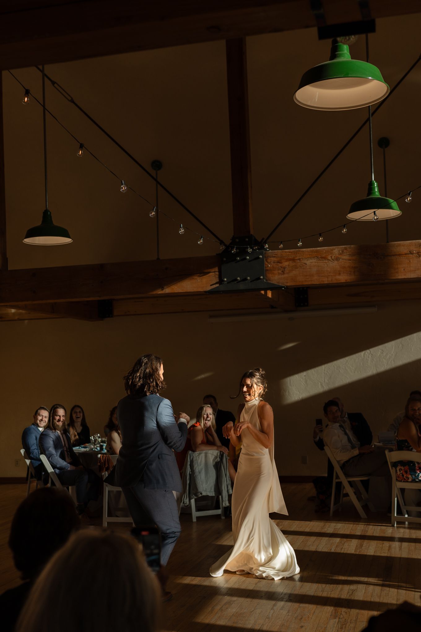 Wedding celebration in a venue with industrial green pendant lights and wooden beam details.