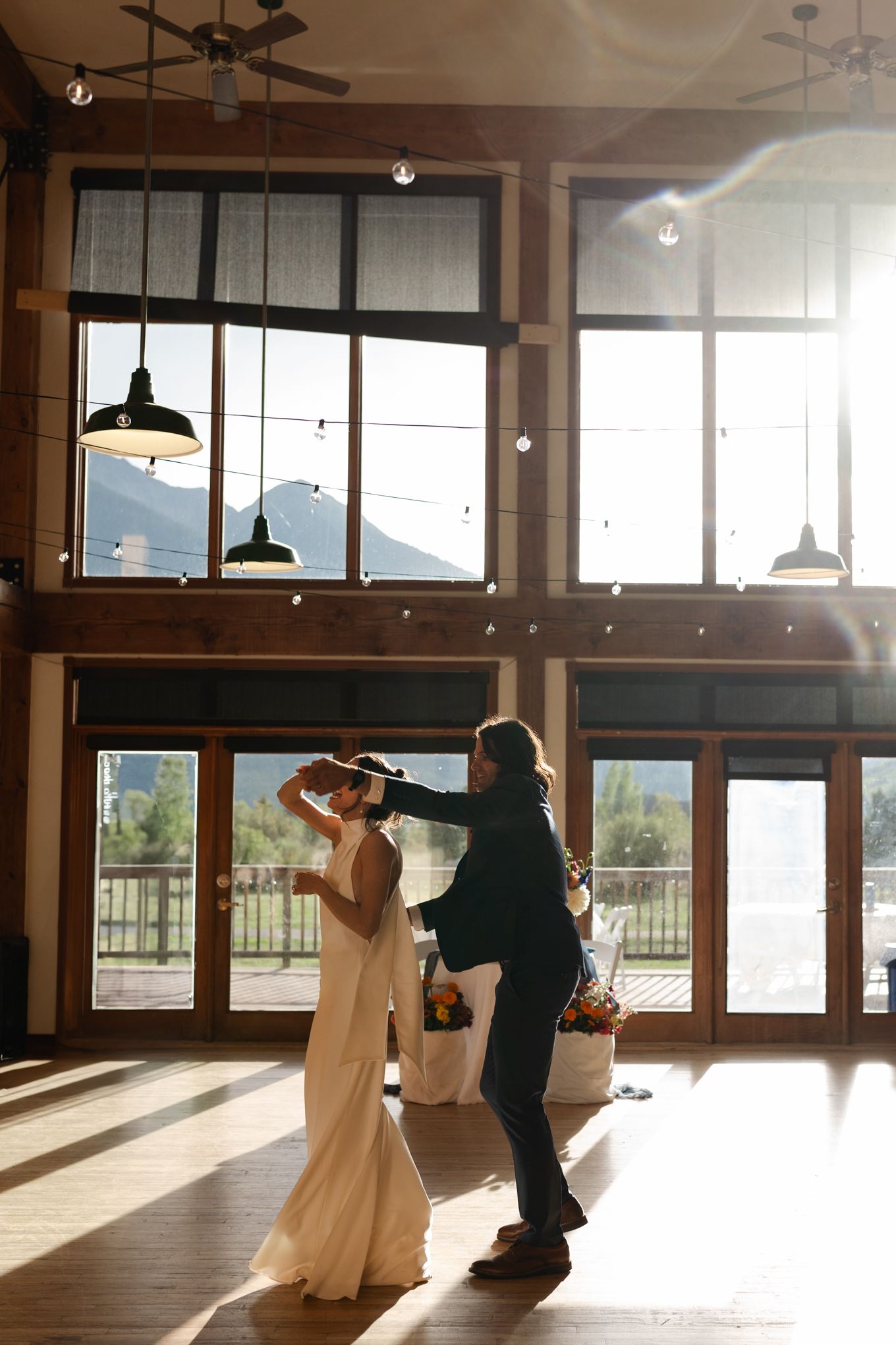 Sunlit dance in a mountain lodge venue with floor-to-ceiling windows and pendant lighting.
