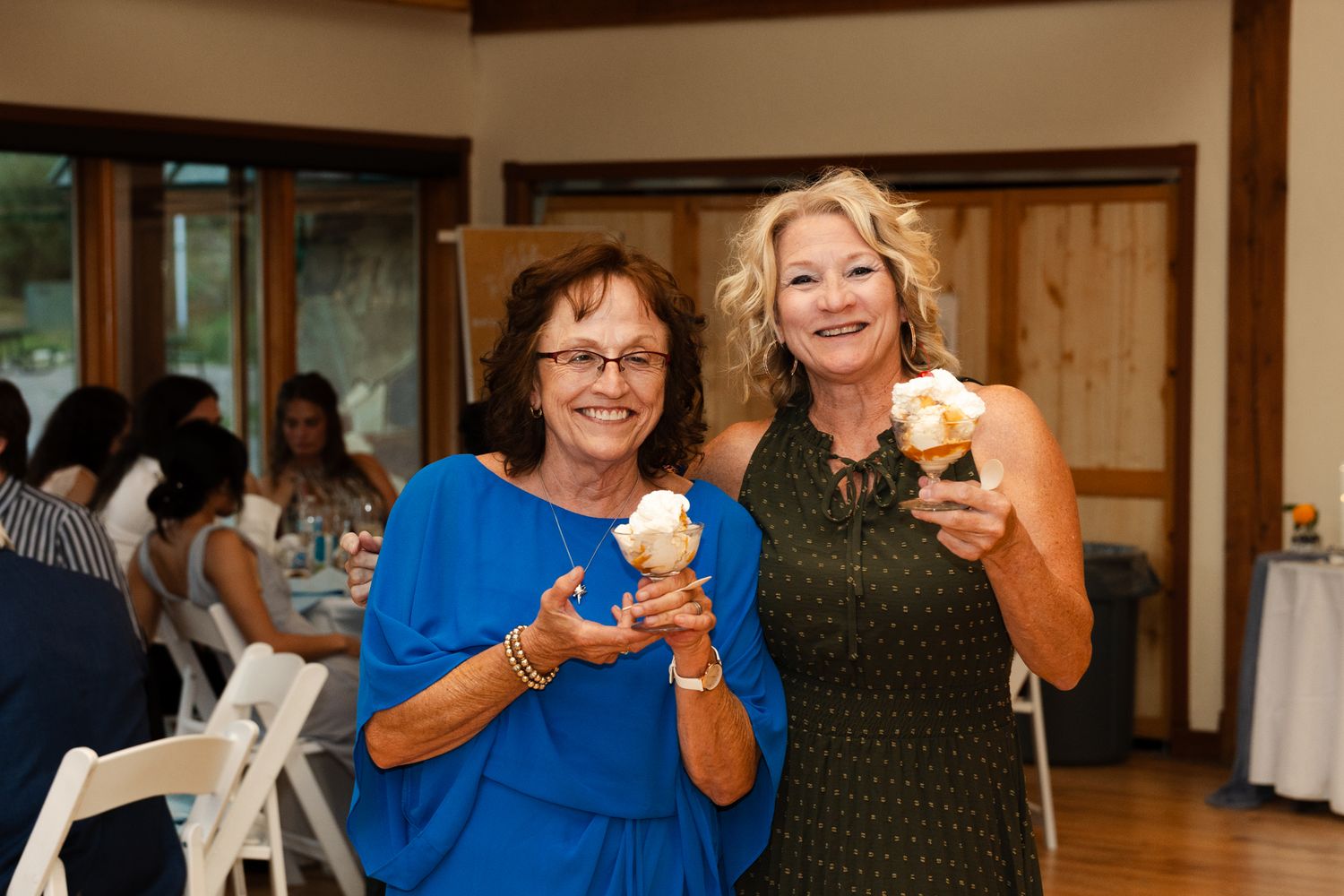 Two guests enjoying ice cream treats at an indoor wedding reception.