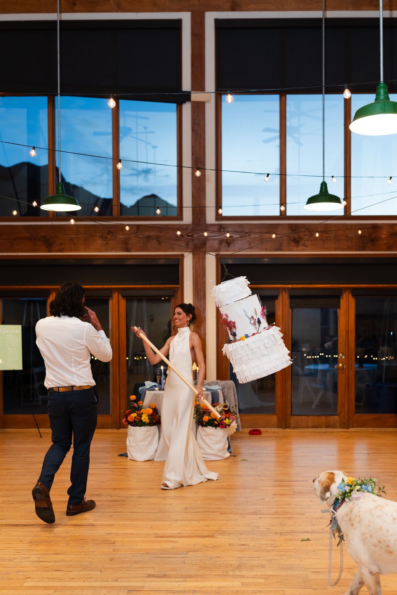 Wedding couple posing for photos in a rustic venue with mountain views and string lights.