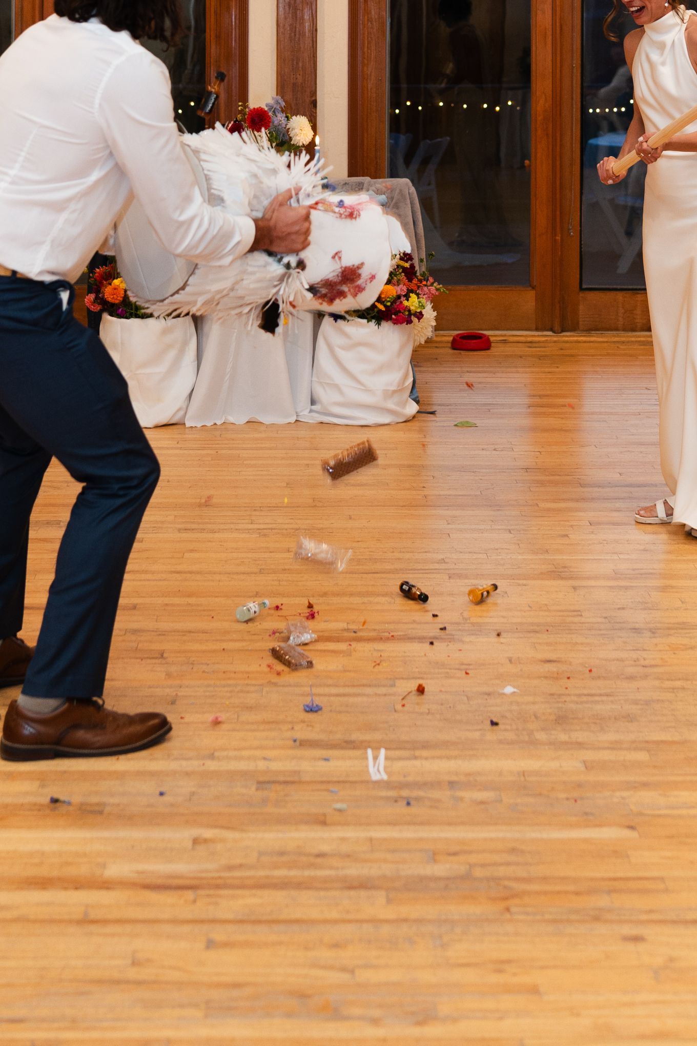 A couple at a wedding reception celebrates with cake on a hardwood floor.