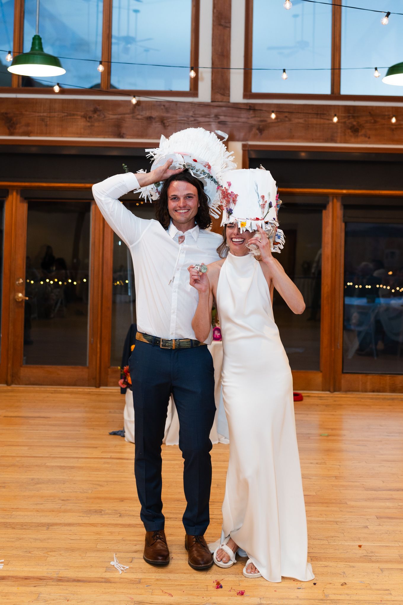 Playful wedding celebration with white decorations in a venue with string lights.