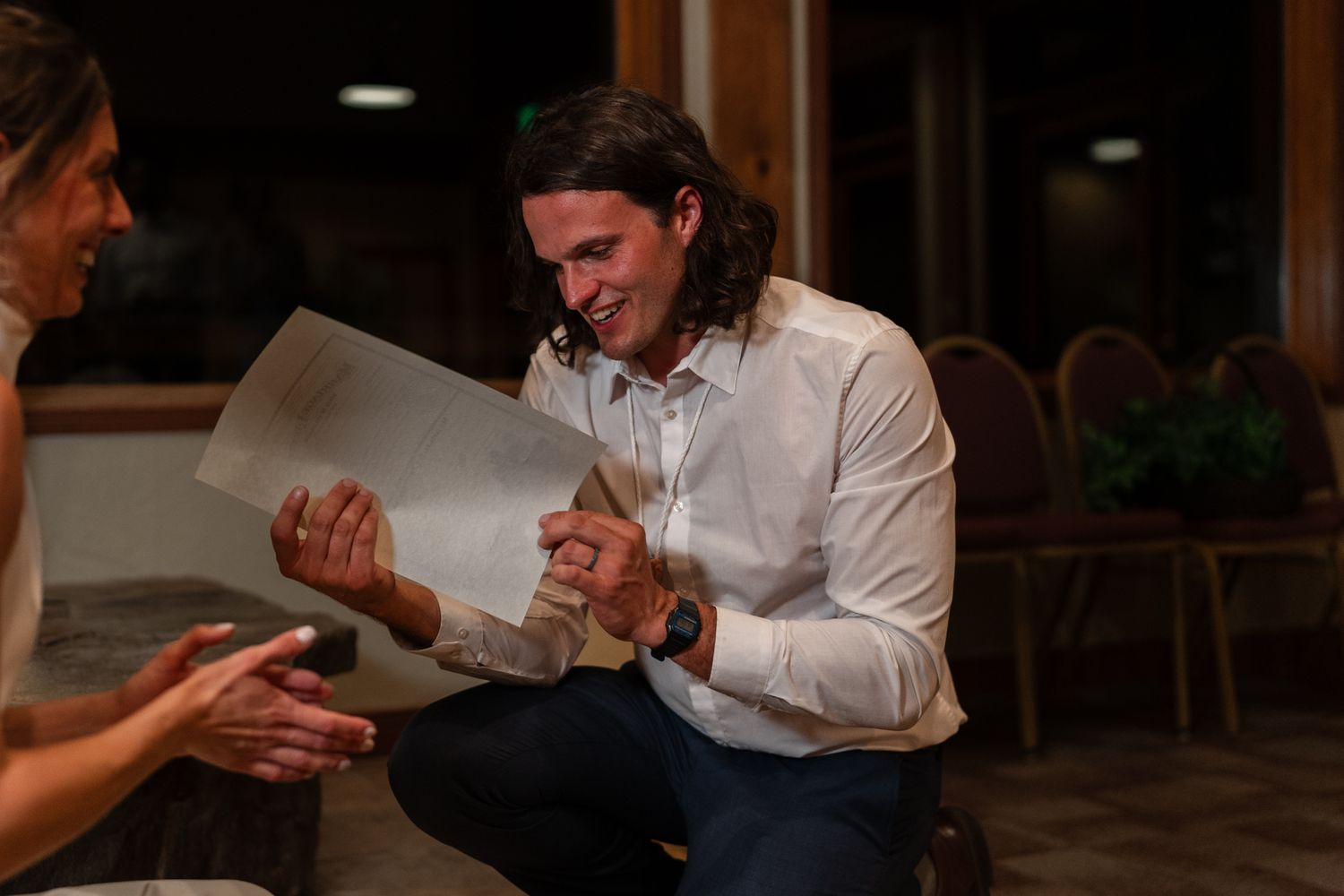 Wedding couple share a joyful moment while looking at their marriage certificate together.