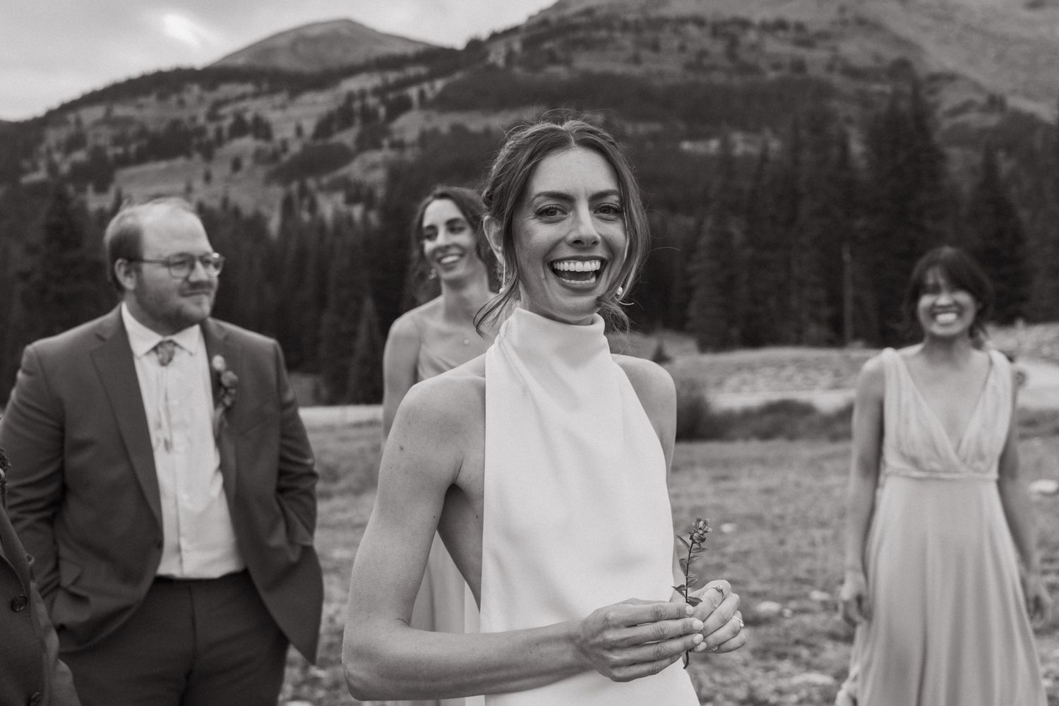 Black and white wedding portrait showing elegantly dressed guests in a mountain setting.