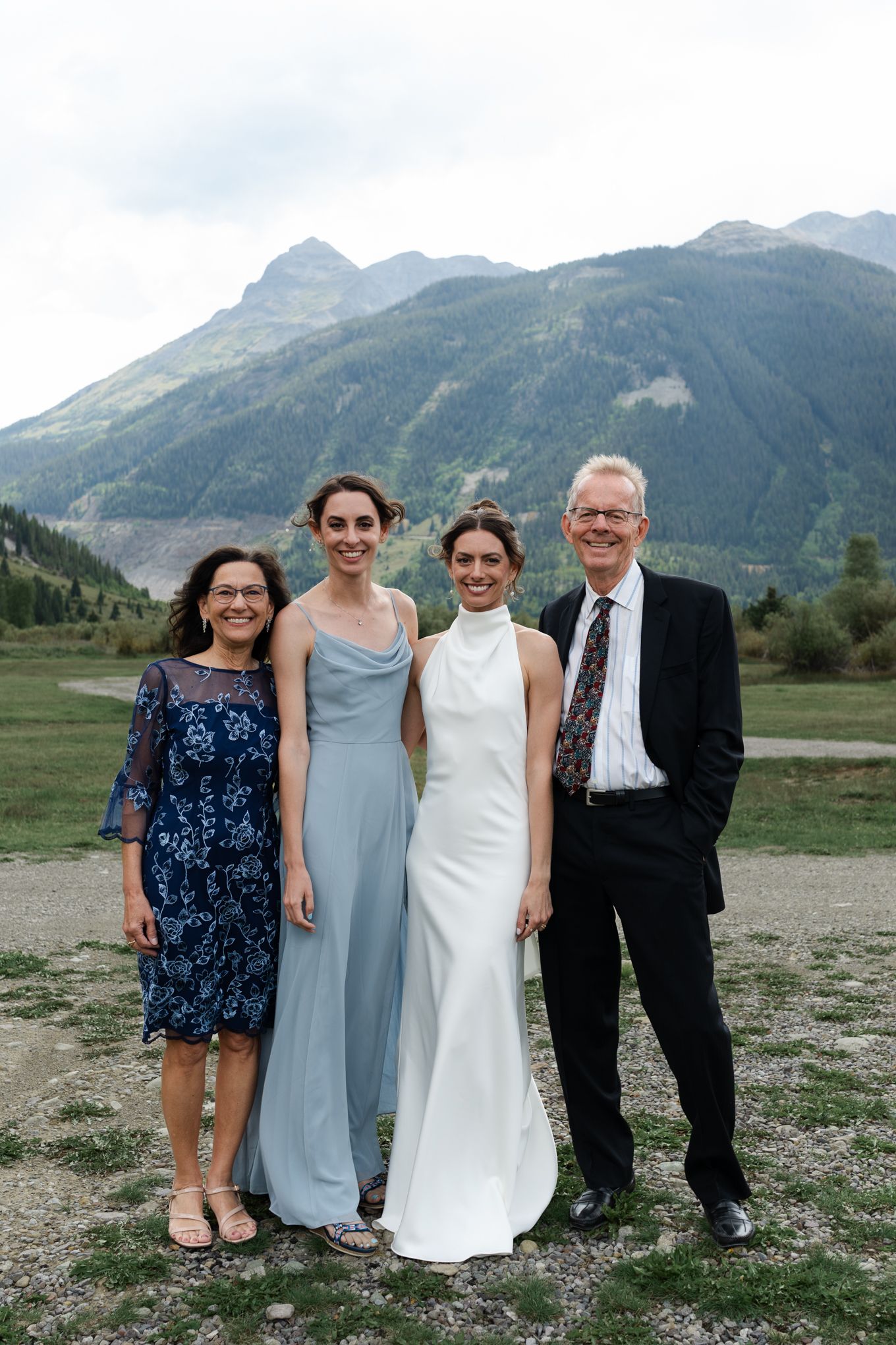 Wedding party poses together in front of majestic mountain peaks on a cloudy day.