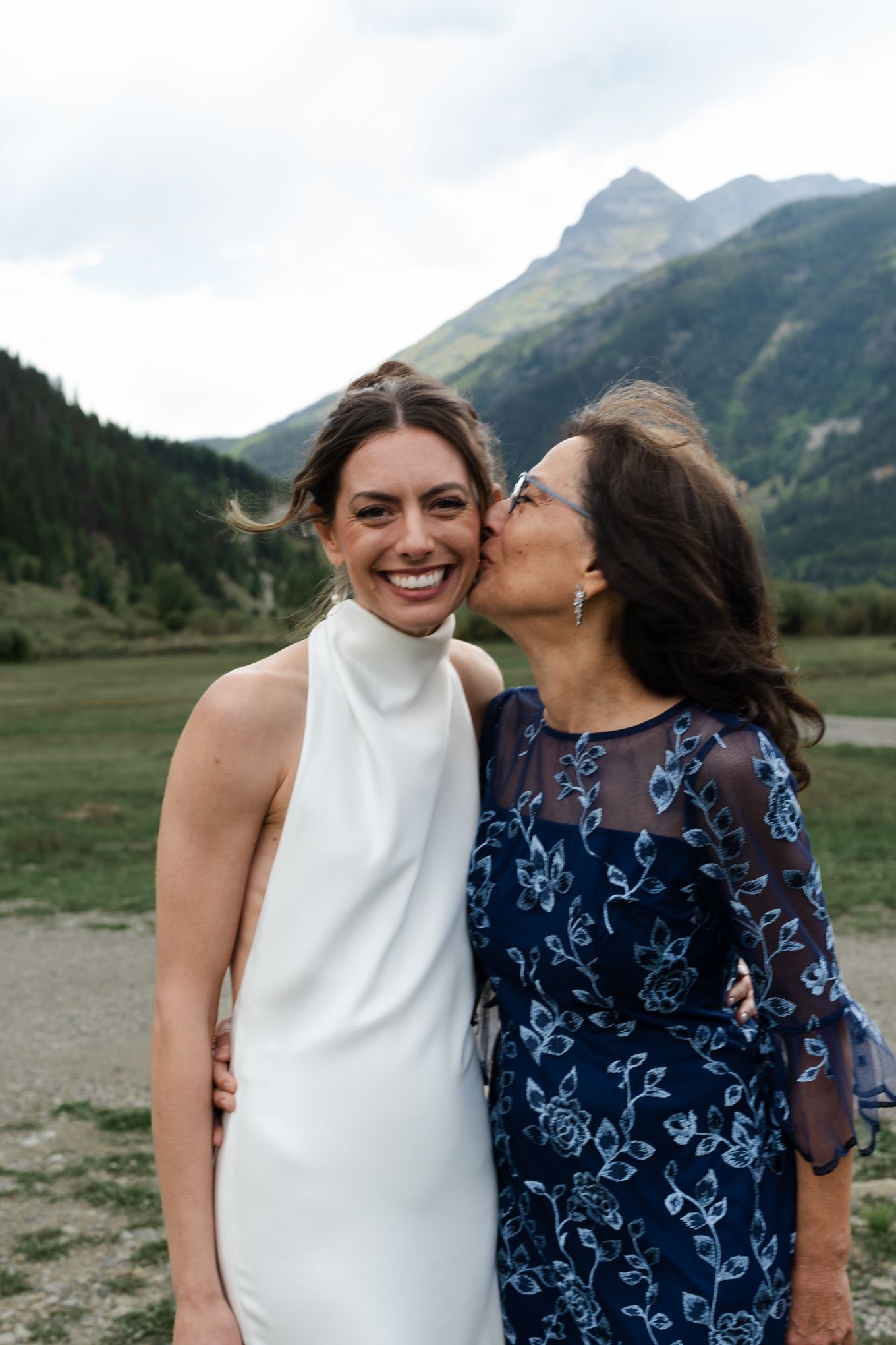 A touching moment of affection captured against scenic mountain landscape.