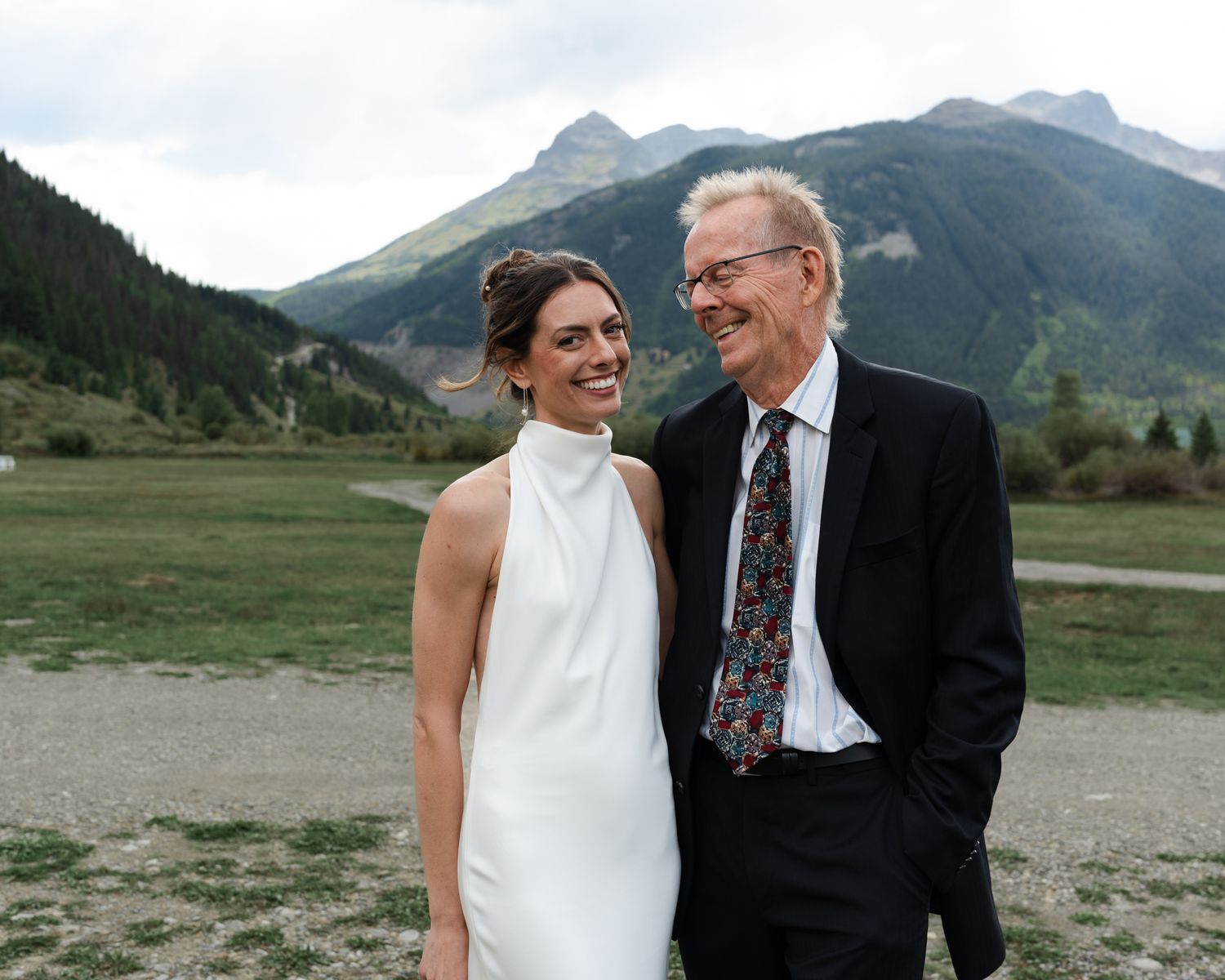 A heartwarming moment between two wedding attendees with mountains in the background.