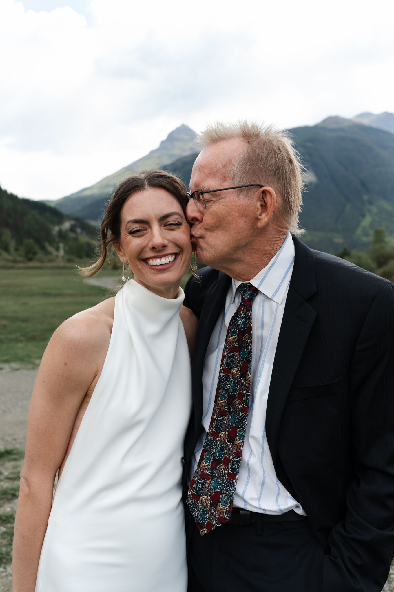 A tender moment shared between wedding attendees with scenic mountain backdrop.