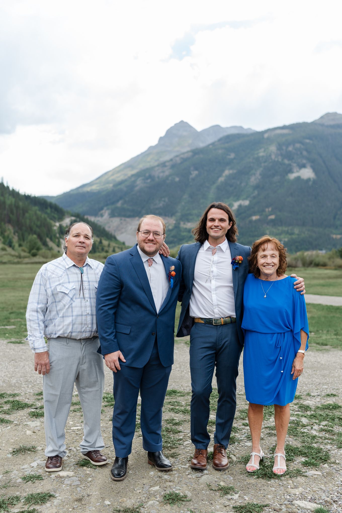 Four people pose together for a group photo with mountains in background.
