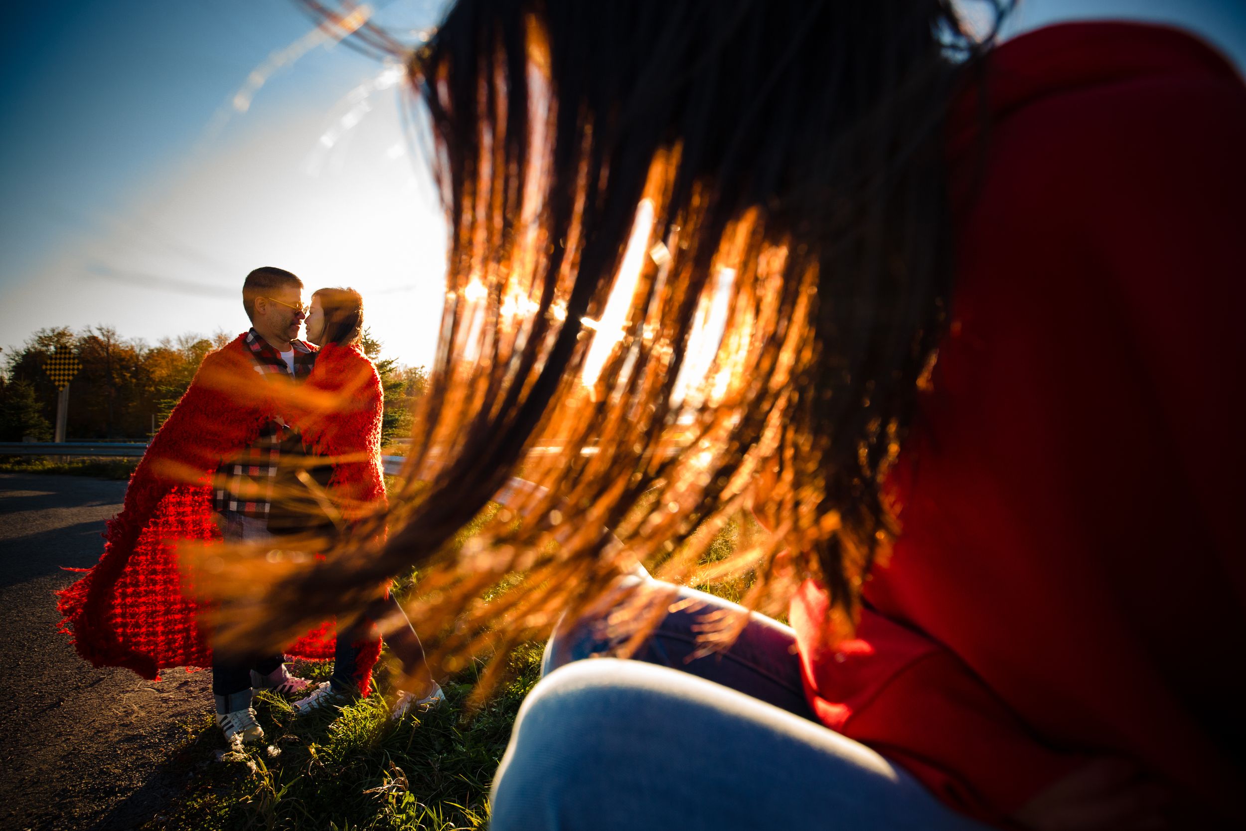 Blurred scene of couple in red garments sitting together outdoors during golden hour sunset lighting.