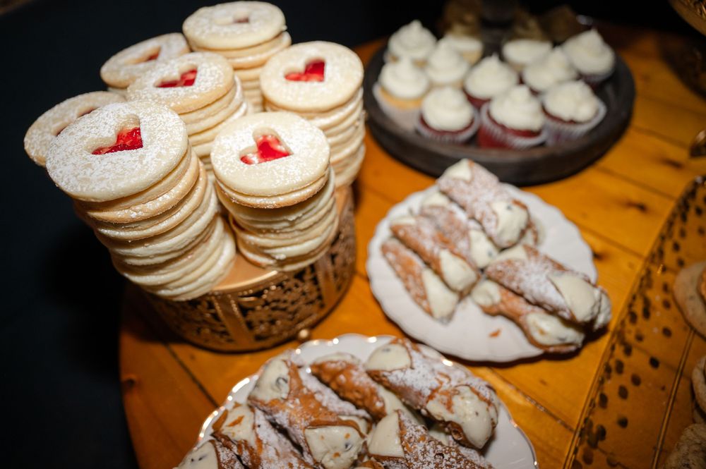 Assorted homemade desserts including chocolate crinkle cookies and sugar cookies decorated with red heart shapes.