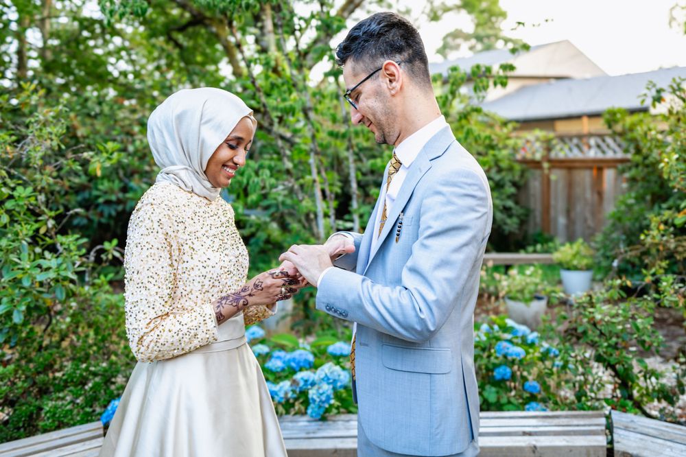 A couple celebrates their engagement in a garden setting with blue hydrangeas and greenery in the background.