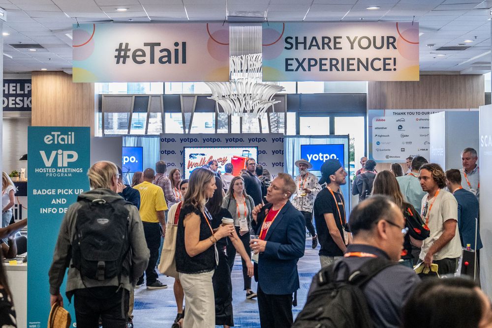 Busy eTail conference exhibition hall with attendees and vendor booths.