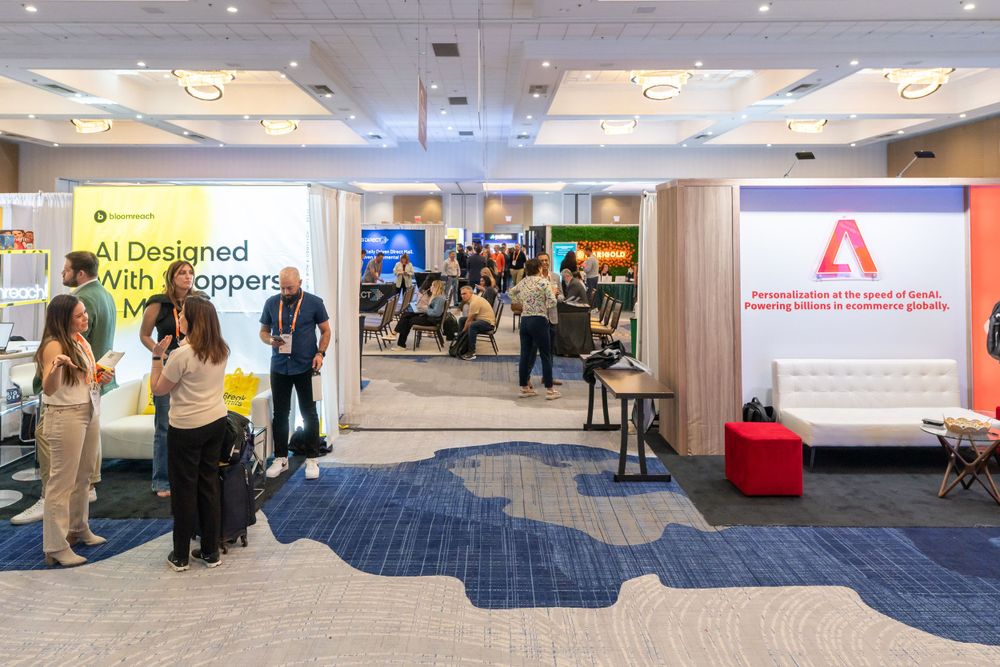 Conference exhibition space with branded displays and attendees networking.