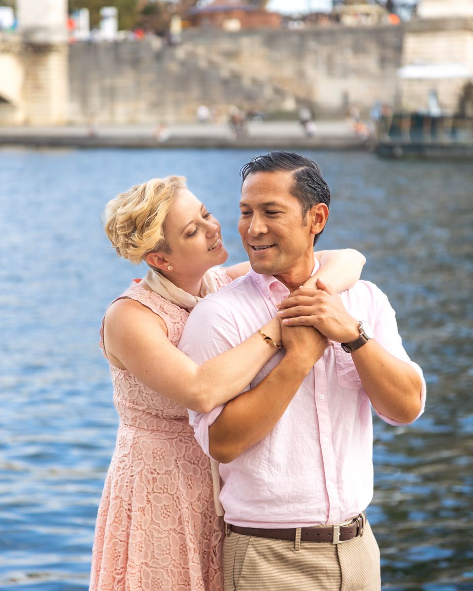 A couple in pink and white dancing by the Seine River in Paris.