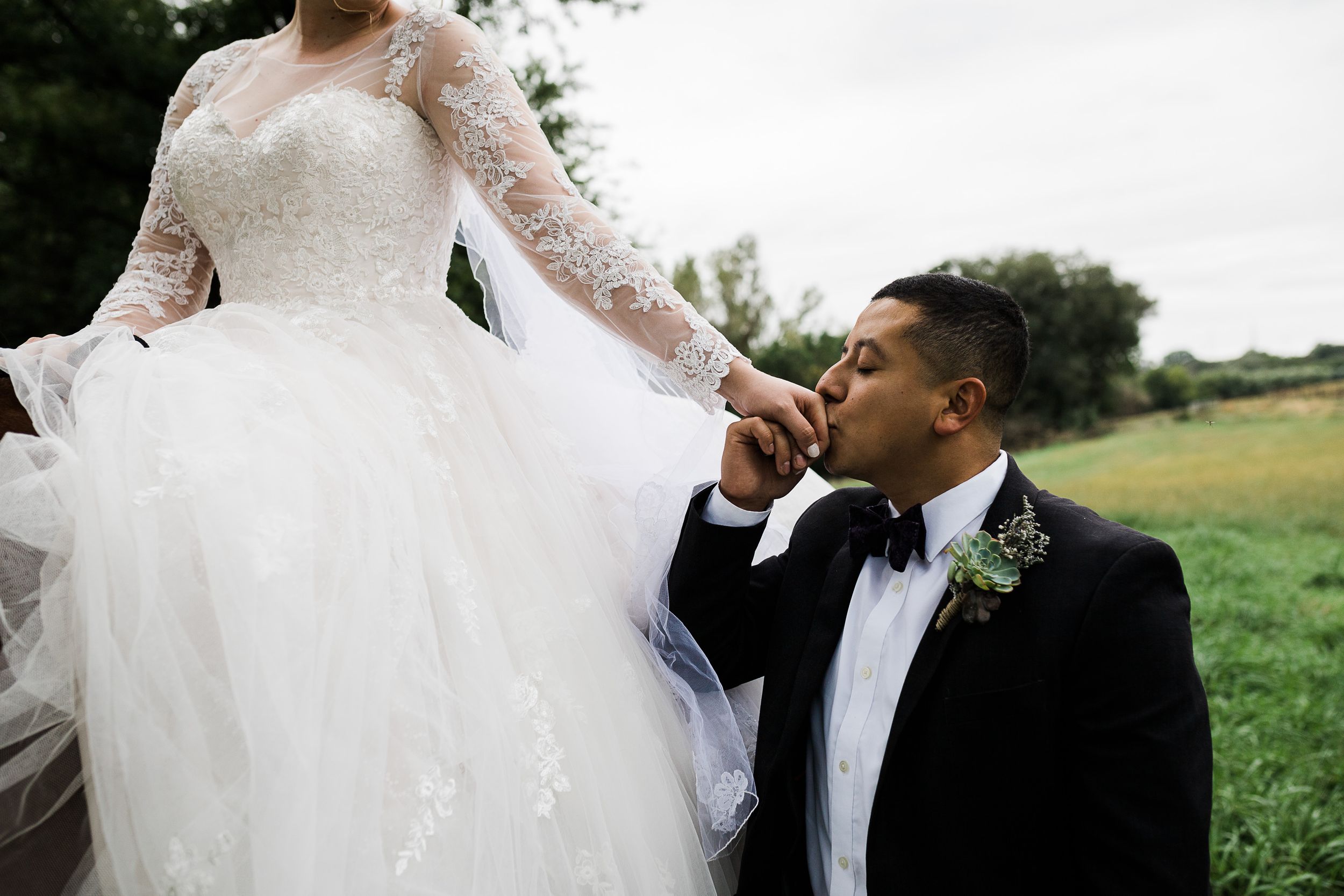 Groom kisses bride's hand as she sits on horseback by Hudson Valley photographer