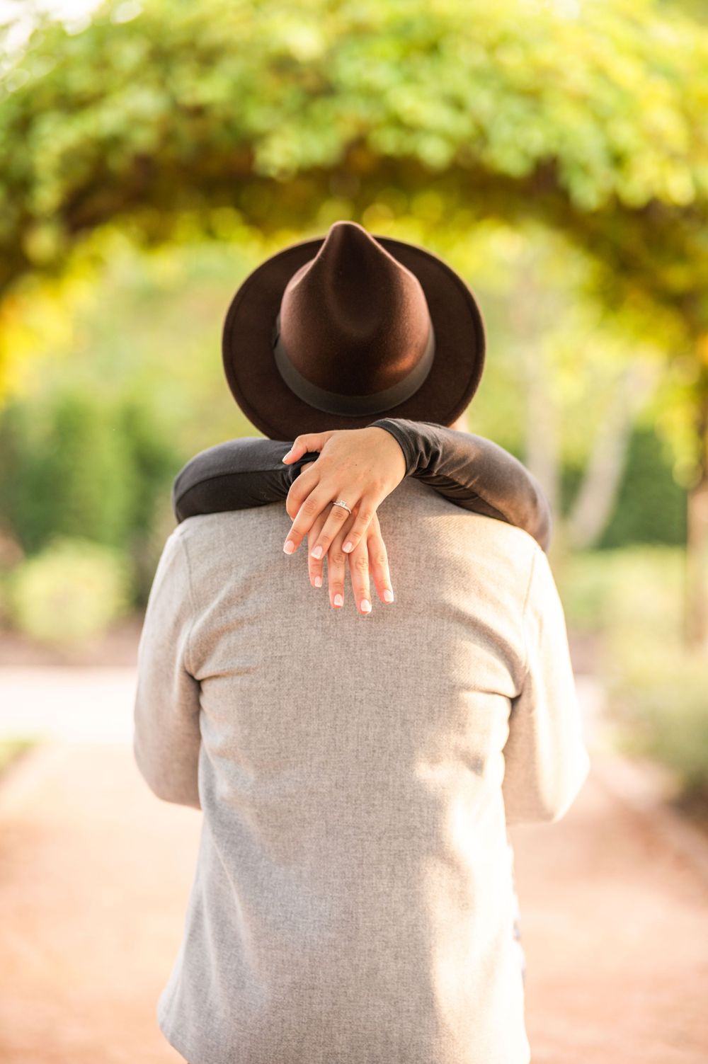 summer engagement groom back with bride's hands
