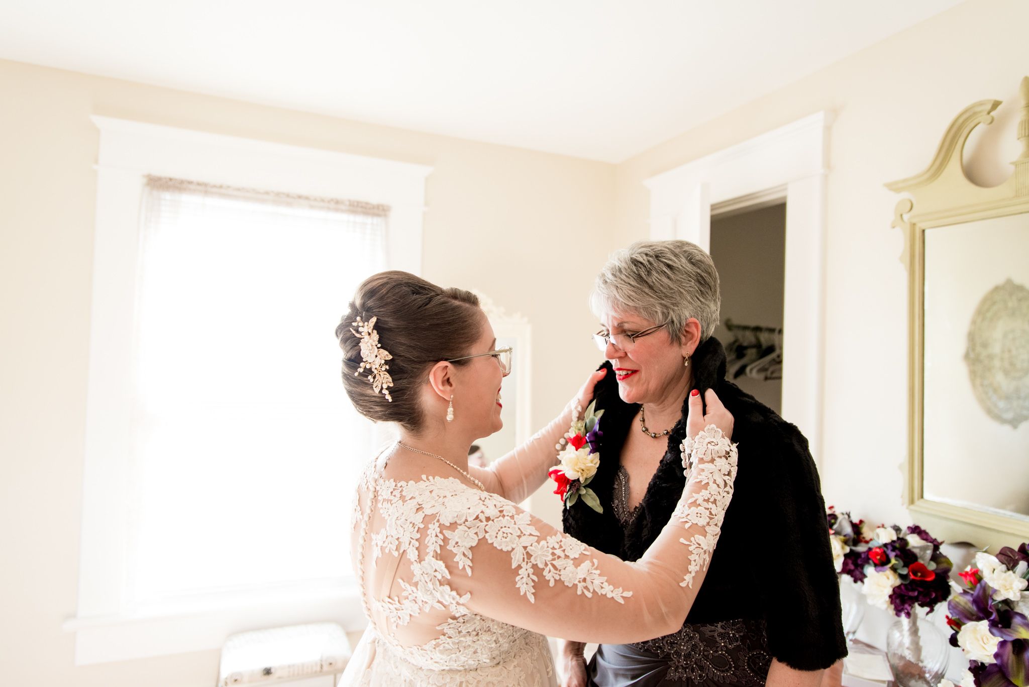 bride in wedding dress fixing mother's black fur shawl for fall wedding in Chicago