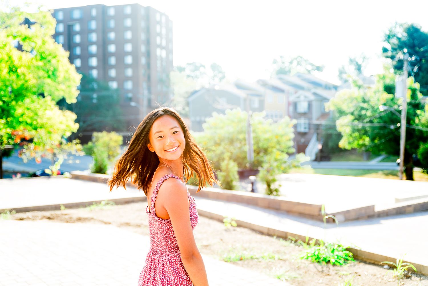 high school Chicago senior in red dress flipping hair in a a Chicago park