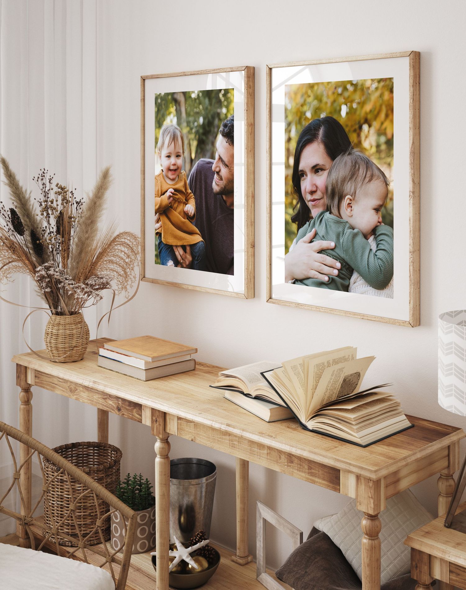 Rustic console table decorated with dried pampas grass and framed photographs beneath two warm-toned wall portraits.