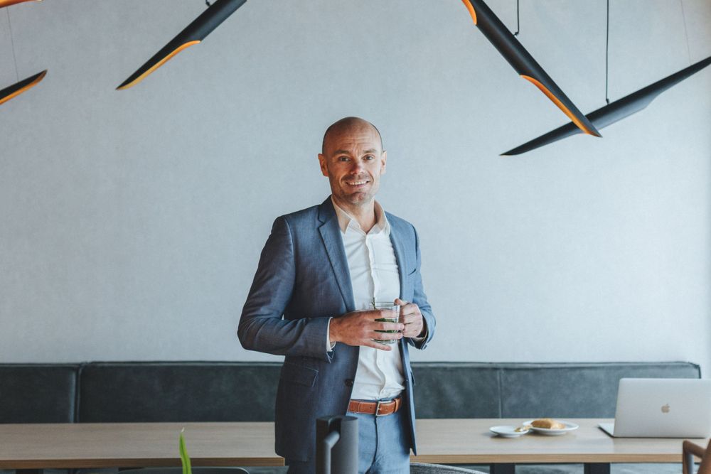 Man in pak staat met een kopje koffie