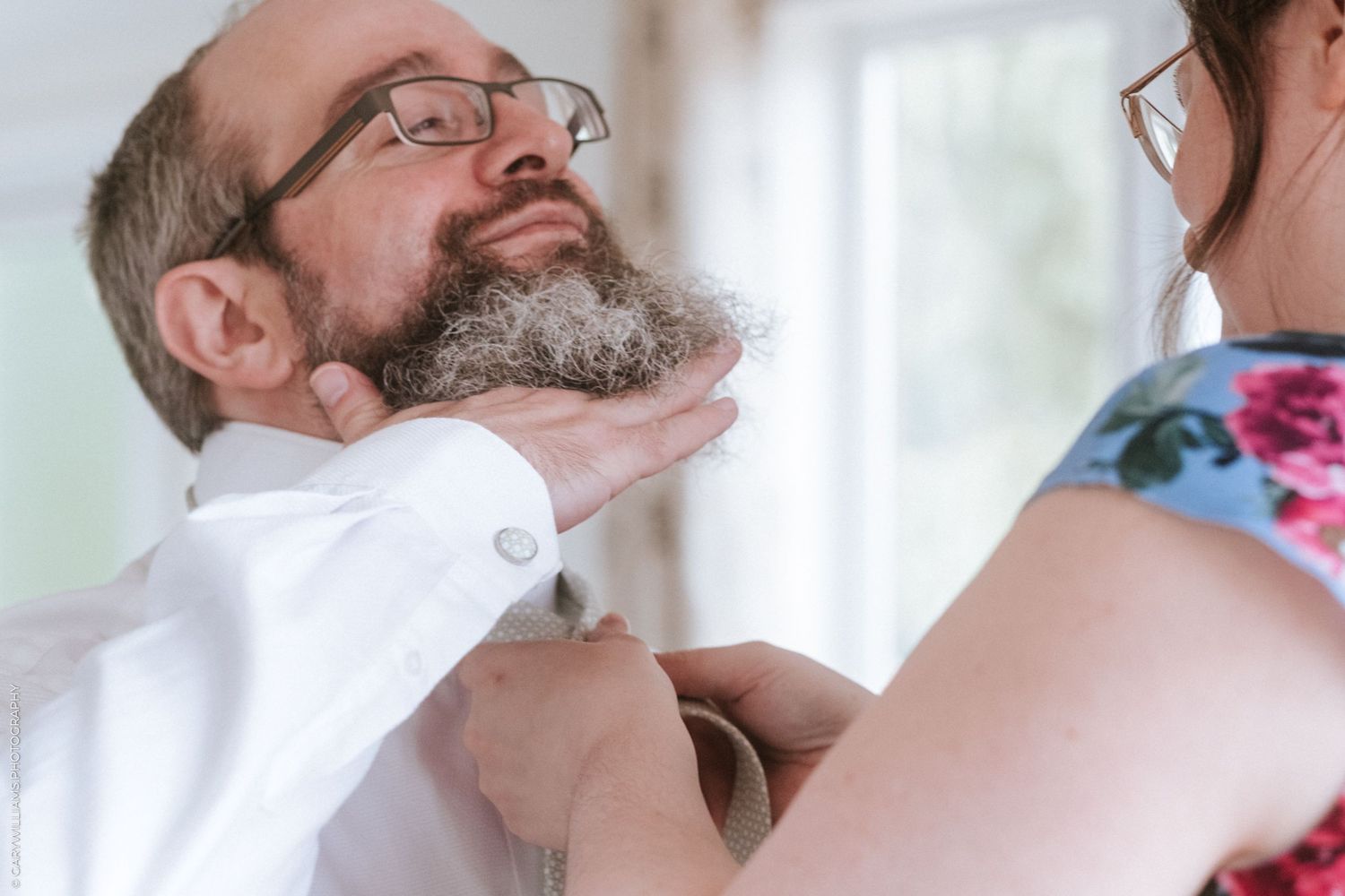 Documentary wedding photography of a groom getting his tie done