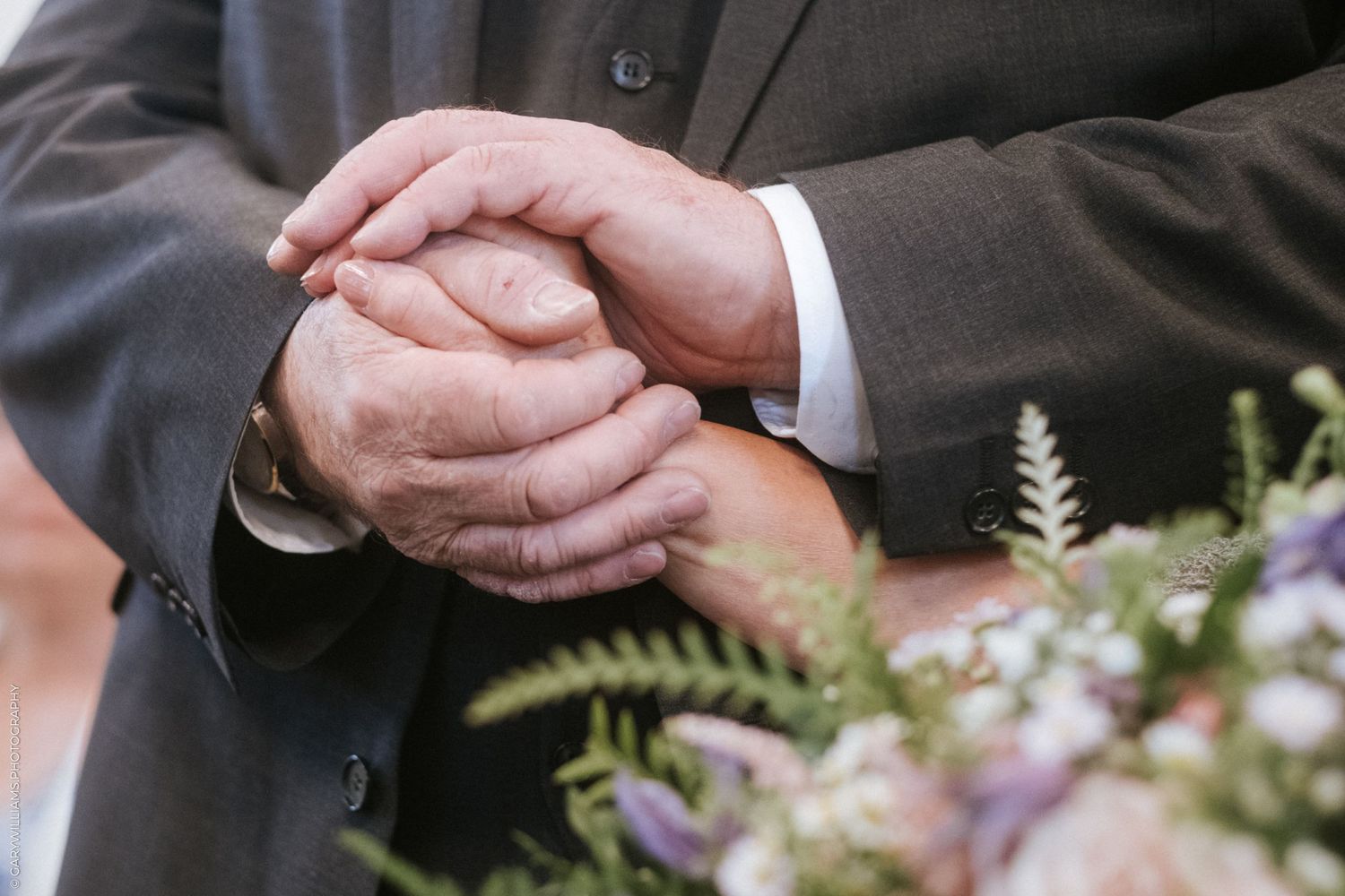 Documentary wedding photography of a husband holding his wife's hand