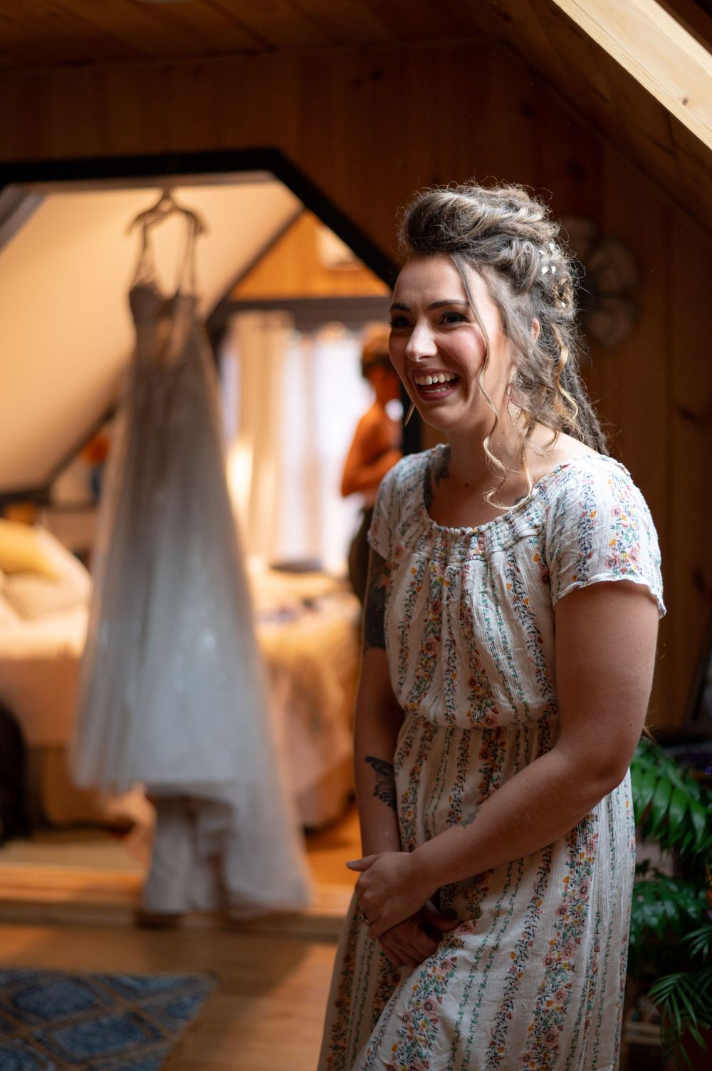 A wedding dress hangs in the background while someone laughs in a floral dress.