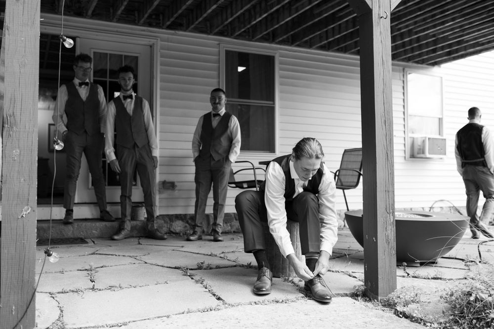 Black and white photo of people gathering on a covered porch during an event.