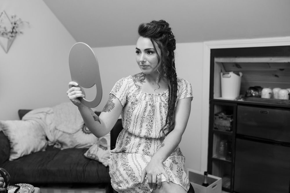 Someone in a floral dress looks at their reflection while getting ready in a bedroom.