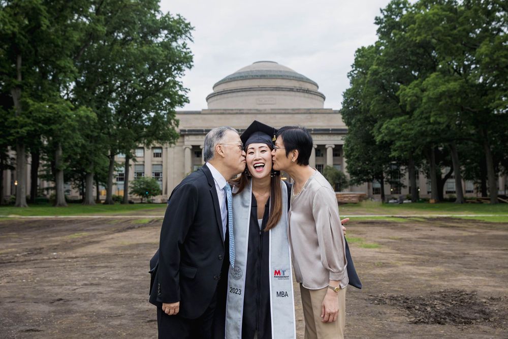 MIT graduation photo with family members kissing the graduate's cheeks in front of Great Dome.