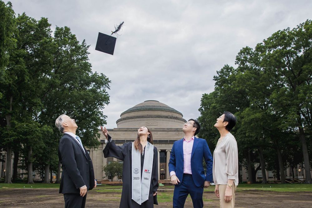 Graduation celebration with group tossing cap in air outside MIT's Great Dome.