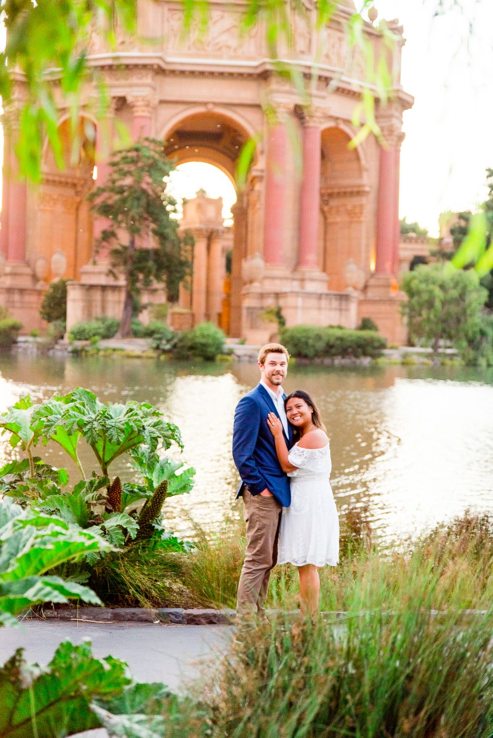 man and woman hugging and smiling in front of Palace of Fine Arts San Francisco engagement pictures