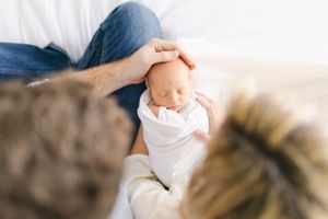 Space Coast Baby photographer - mom and dad holding baby on bed portrait