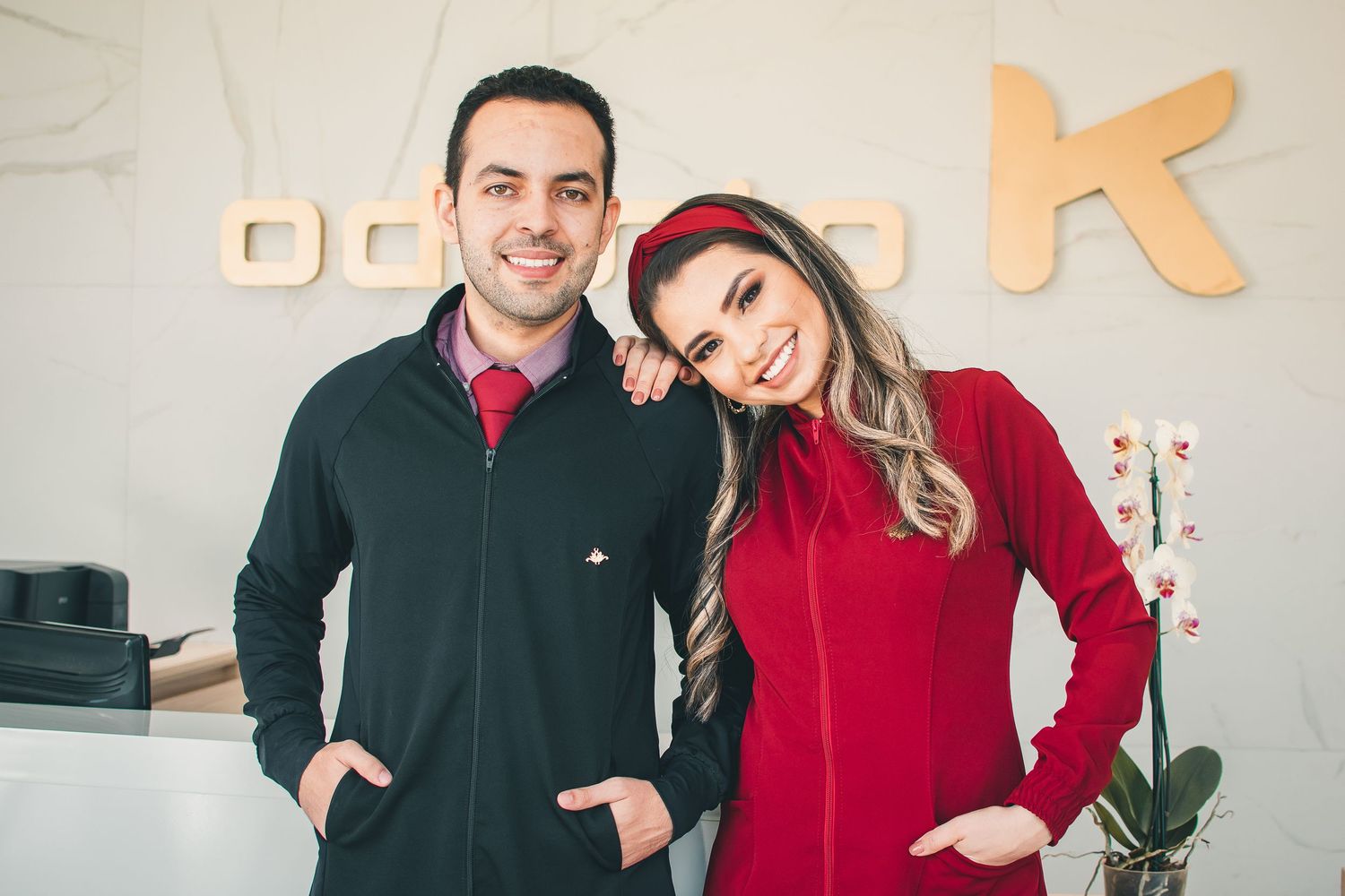 Two people in matching fleece jackets standing together in an office space.
